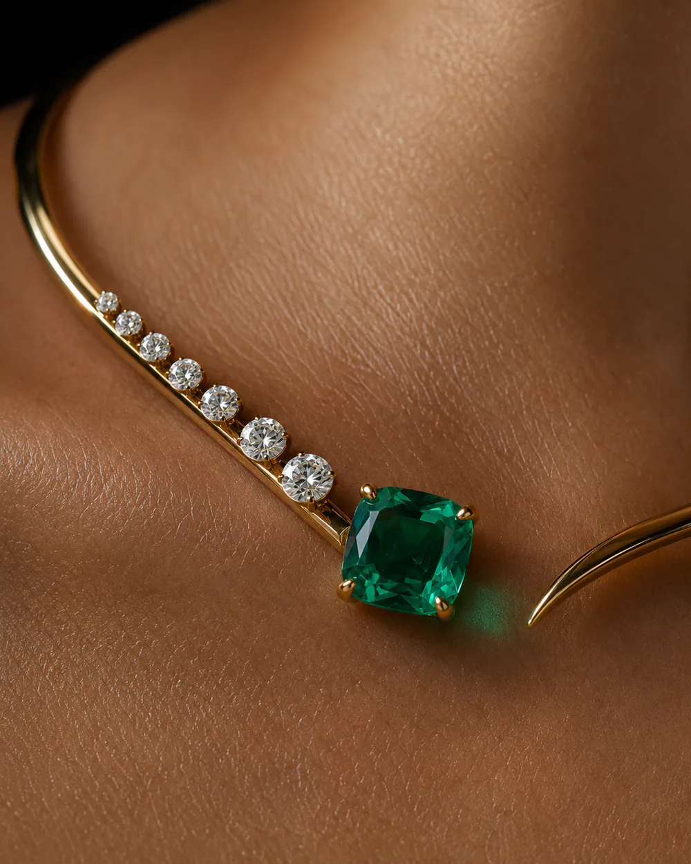 Macro della collana in oro con smeraldo appoggiata sulla pelle